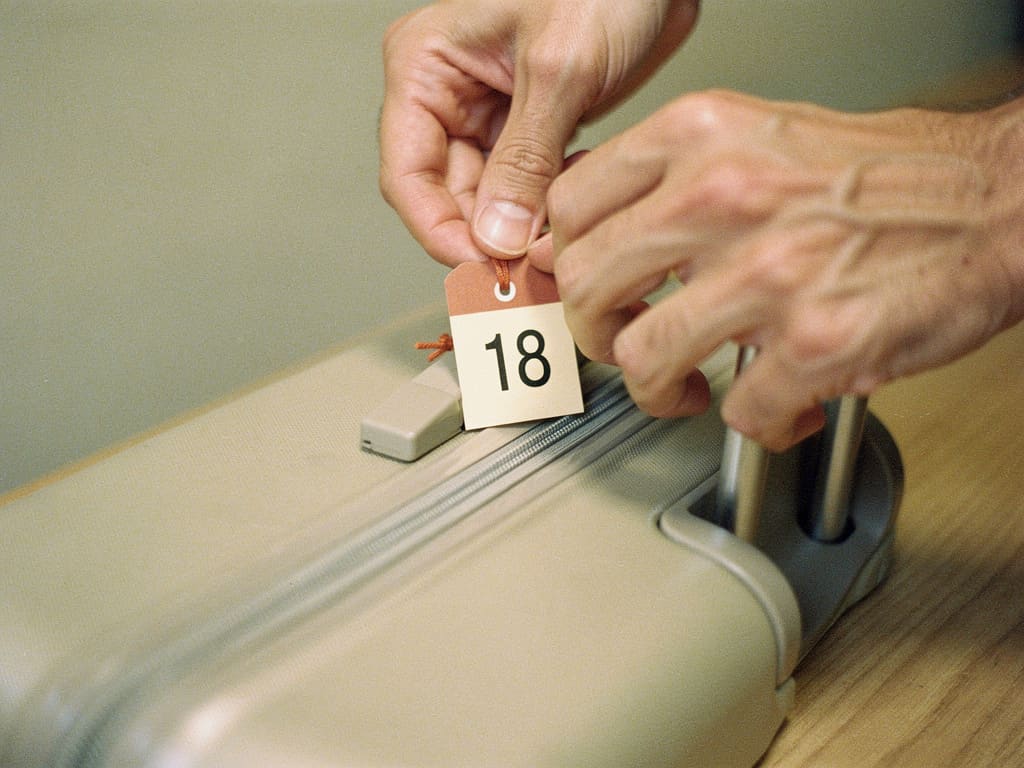Mani che applicano un'etichetta numerata su una valigia